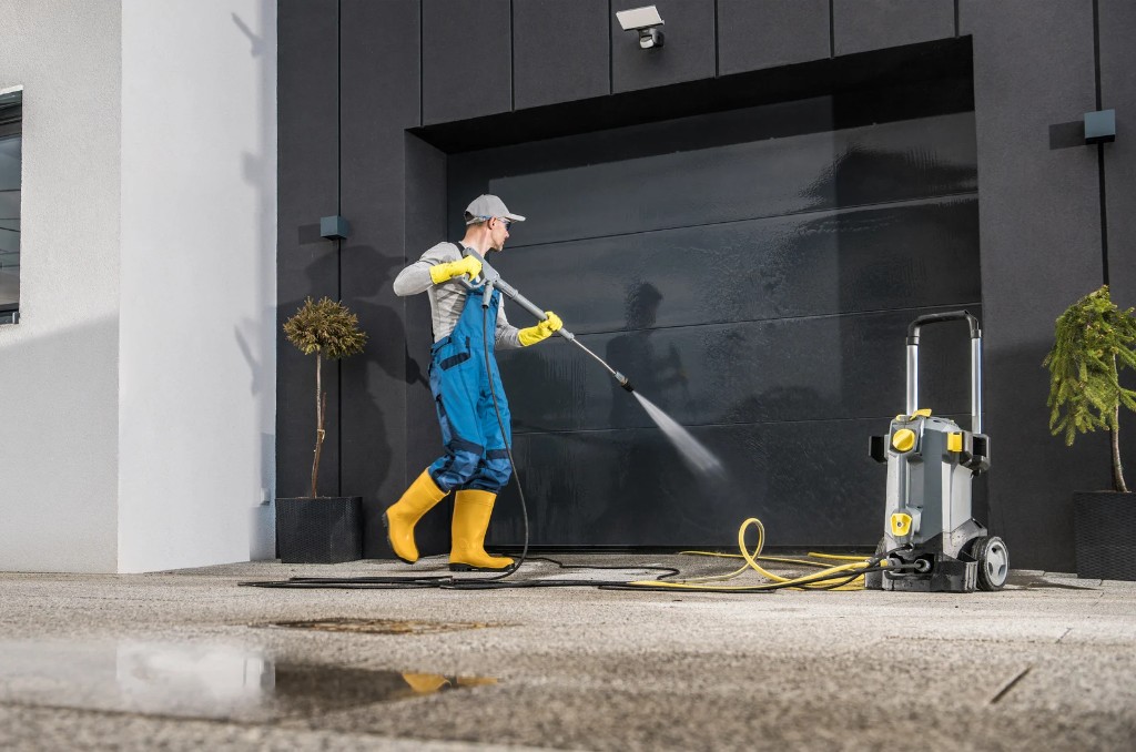 Worker pressure washing a large commercial garage door