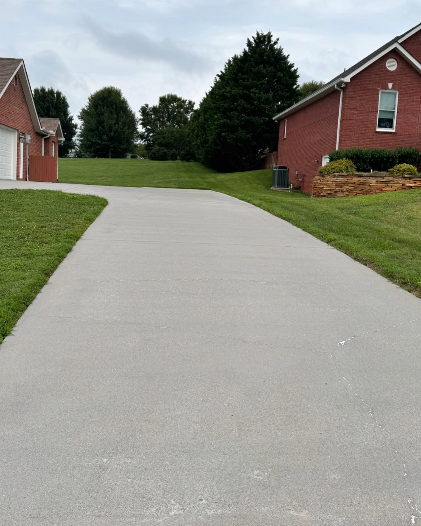 Bright clean concrete driveway between red brick homes